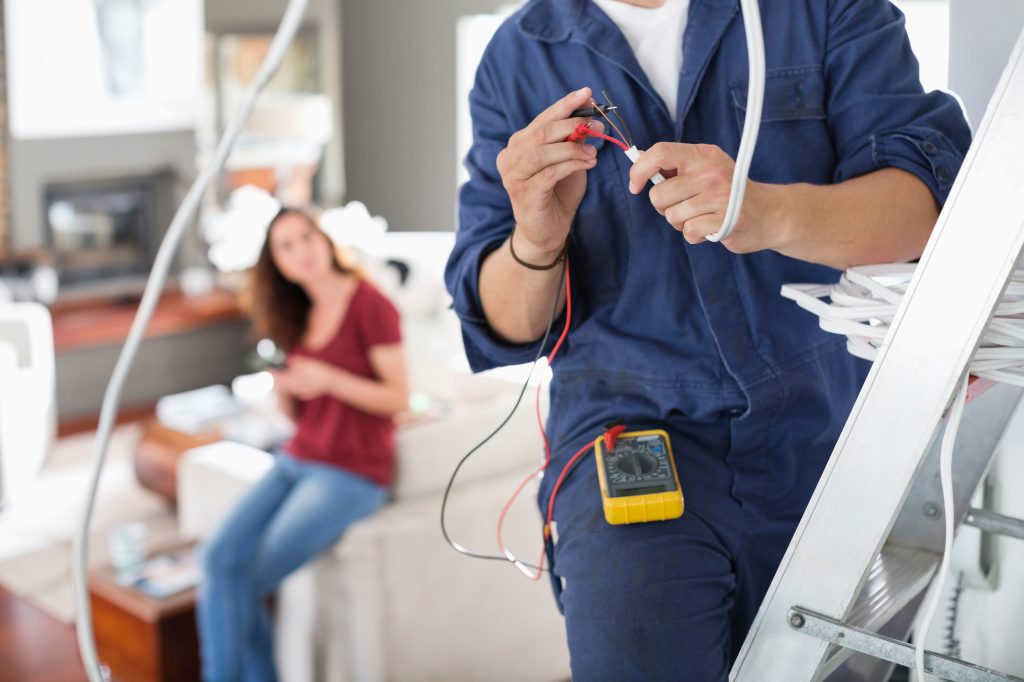 a man on a ladder working on wires as an Electrical Contractor in Margate, FL, Fort Lauderdale, Sunrise, FL, Parkland, Boynton Beach, Boca Raton